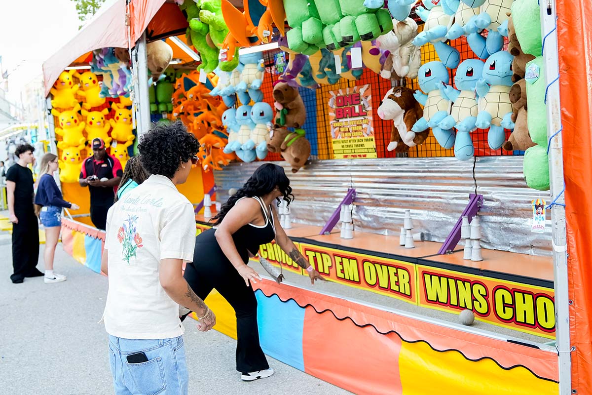 Player throwing ball to knock down bottles at fair