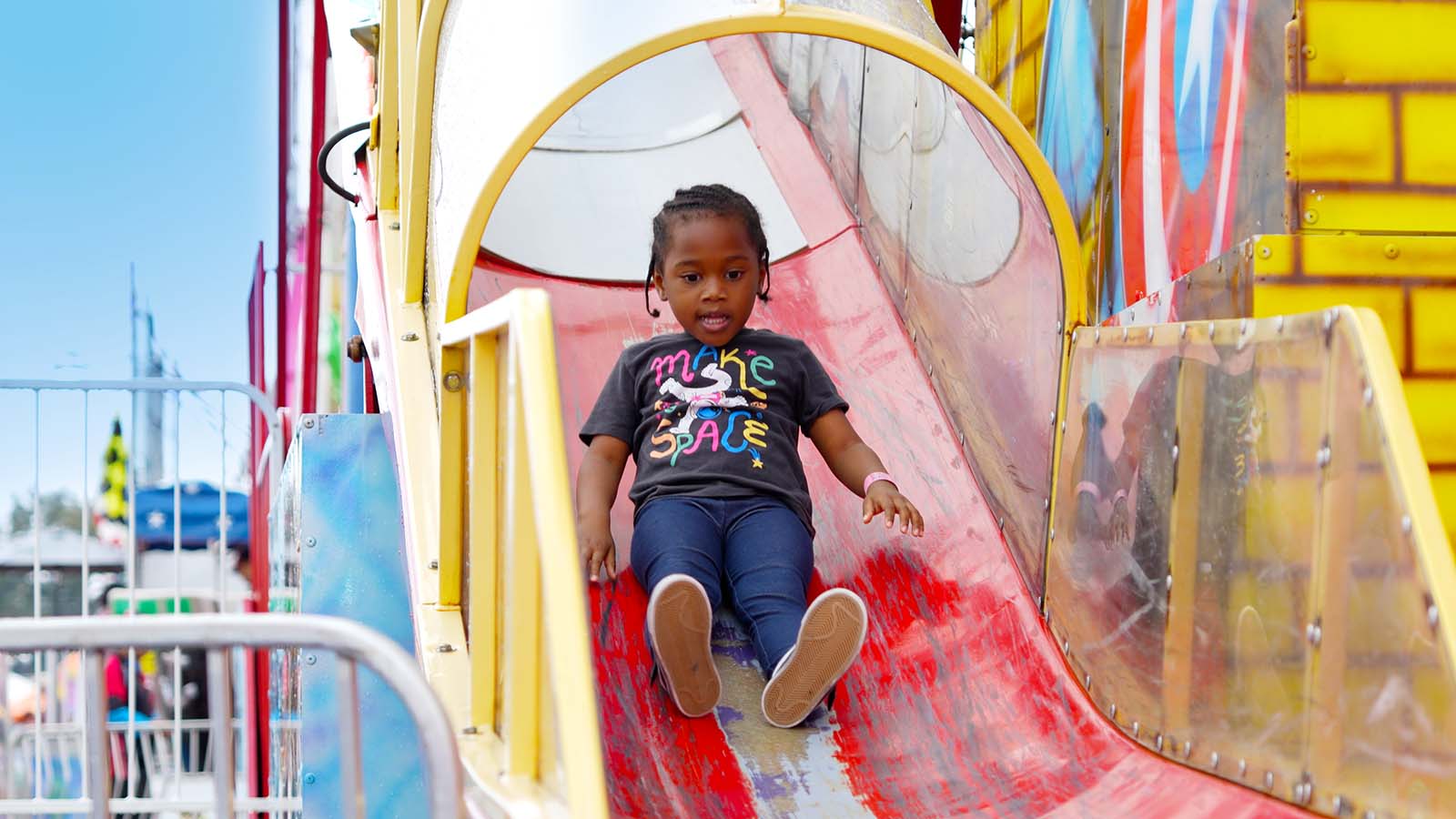 Young child slides down a Talley Amusements slide at the state fair